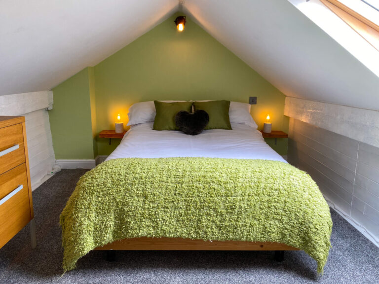 Cosy attic double bedroom with sage-green wall in the 2-Bed Apartment