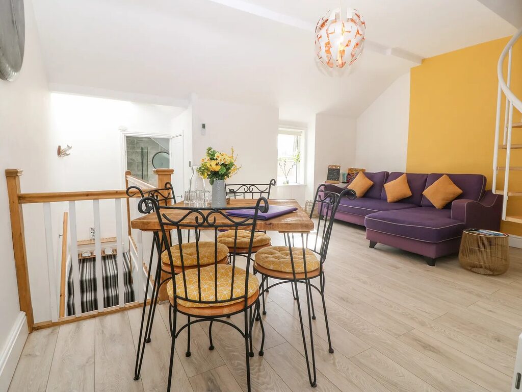 2-Bed Apartment open-plan living room with mustard feature wall and dining table