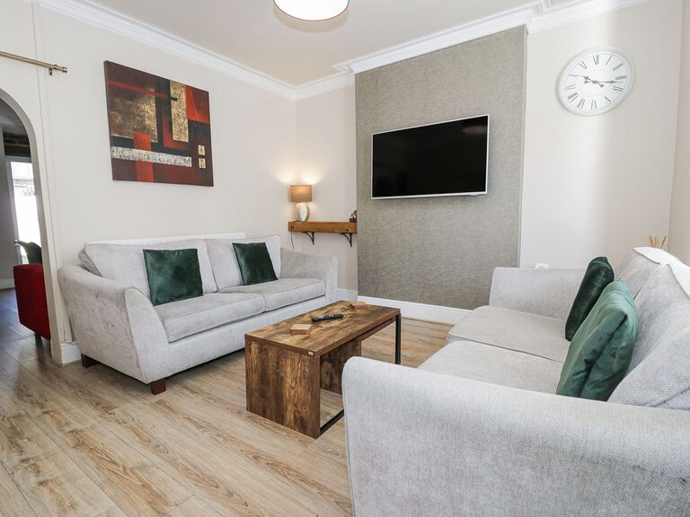 3-Bed Garden Apartment sitting room with grey sofas and wooden coffee table